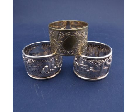 A pair of late Victorian ornate silver napkin rings repousse with tavern scenes.  London 1898.  Maker's mark "AG".  A plated 