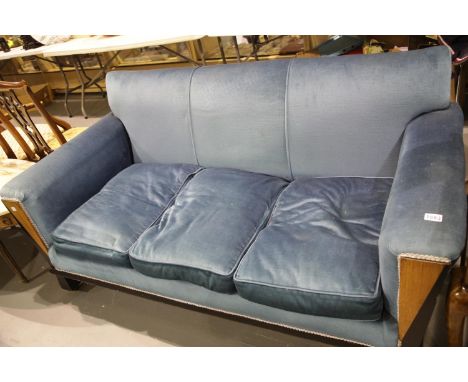 An Art Deco walnut framed three seater settee, upholstered in blue, in the style of Waring and Gillows. Not available for in-