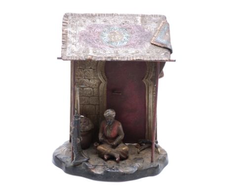 Franz Bergmann style figure of an ivory poacher smoking a pipe with tusks and guns beneath a carpeted shelter, marked AP, mad