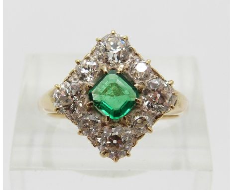 A late Victorian/ early Edwardian ring set with a square step cut emerald of approximately 0.31ct surrounded by eight old cut