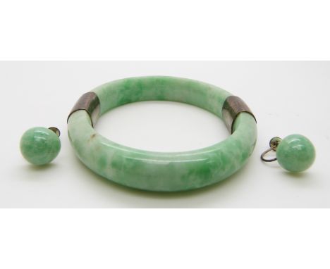 A jadeite bangle with white metal fittings and jadeite earrings with silver fittings