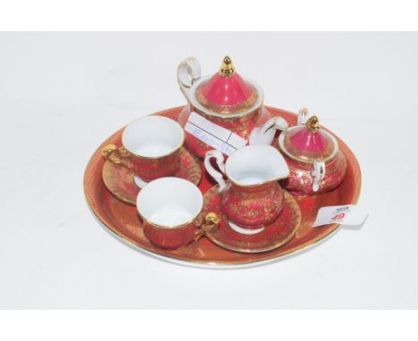 MINIATURE CROWN PORCELAIN TEA SET AND TRAY COMPRISING TEA POT, MILK JUG, SUGAR BOWL, TWO SMALL CUPS AND SAUCERS ON RED AND GI