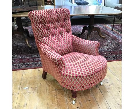 A modern low library armchair with button back, upholstered in a stylised flowerhead fabric, with turned front supports with 