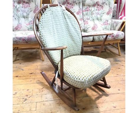 An Ercol dark stained beech spindle back open arm rocking chair, with squab cushion to back and seat, in sage green dotted fa