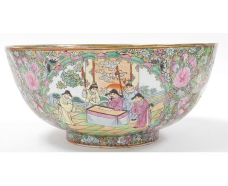 A 20thC Cantonese famille rose porcelain punch bowl, decorated centrally with figures in a garden, within a border of flowers