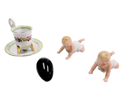 A pair of Gebruder Heubach bisque porcelain piano babies, together with a Limoges porcelain demitasse coffee cup and saucer, 