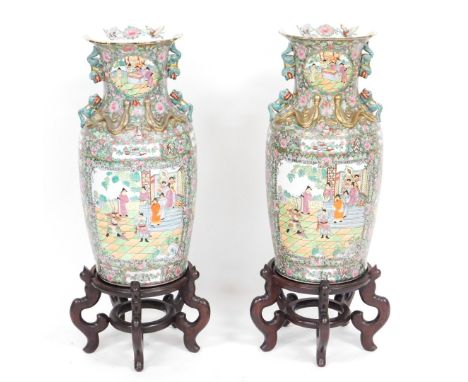 A pair of late 20thC Cantonese famille rose porcelain vases, on wooden stands, of shouldered ovoid form, with double dog of f