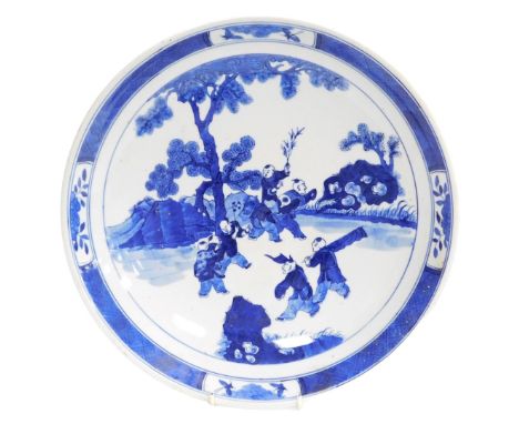 A 19thC Qing dynasty Chinese porcelain charger, decorated in blue and white with various figures in a landscape and a diaper 