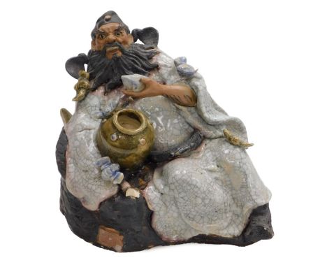 A 19th/20thC Chinese Shiwan figure, wine cup in hand, reclining beside a large barrel of wine (of which he has clearly drank 