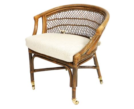 A bamboo and cane tub chair, with a loose cushion seat, raised on cylindrical legs, united by a X frame stretcher, brass capp