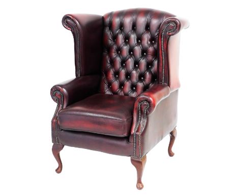 An oxblood leather club armchair, with button back and loose cushion seat, raised on cabriole legs, 74cm wide.