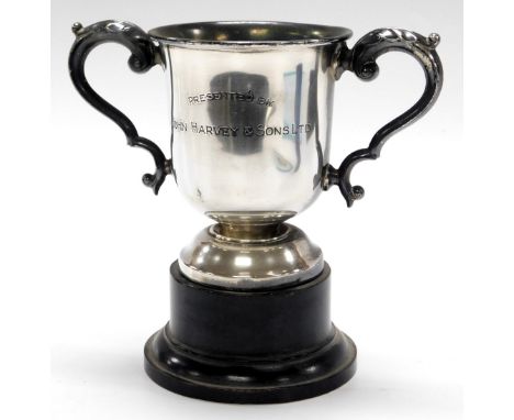 A George V silver twin handled trophy, engraved Presented by John Harvey &amp; Sons Limited, with an ebonised socle, Sheffiel