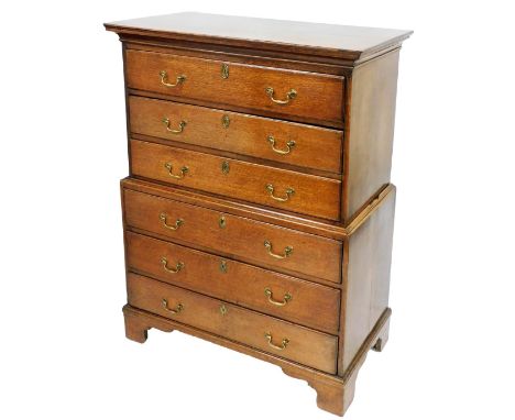 A George III oak chest on chest, the outswept pediment over three long drawers, raised on bracket feet, 131cm high, 101cm wid