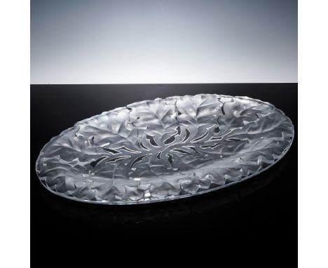 Crafted in fine French crystal, this oval Lalique platter showcases oak leaves in elegant relief. Featuring a dynamic interpl