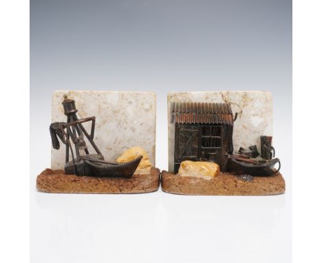 A charming pair of bookends depicting a rustic seaside vignette. One features a small shanty shack with maritime accessories,