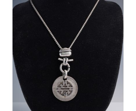 This striking necklace features a long, substantial chain with a toggle-style connector and a bold round medallion pendant fe