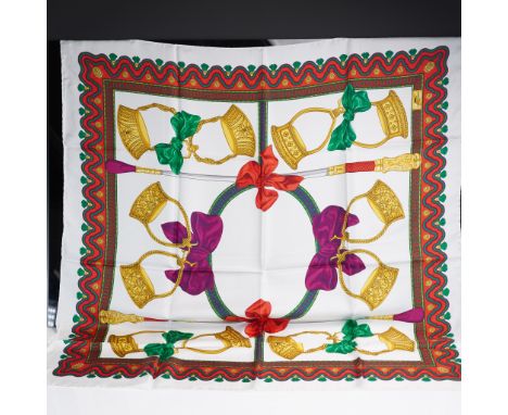 A large, enchanting 100% silk scarf featuring a bold equestrian themed design with golden stirrups, riding crops, and oversiz