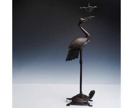 A tall and finely cast Japanese bronze figural candlestick depicting a crane standing atop a turtle, holding a lotus-form can