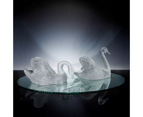This elegant 3-piece Lalique crystal figurine set includes two majestic frosted crystal swans paired with a round beveled-edg