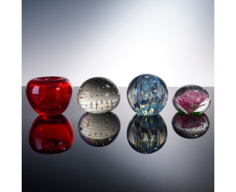 A visually striking collection of four art glass paperweights, each reflecting unique glass artistry. Included is a bold red 