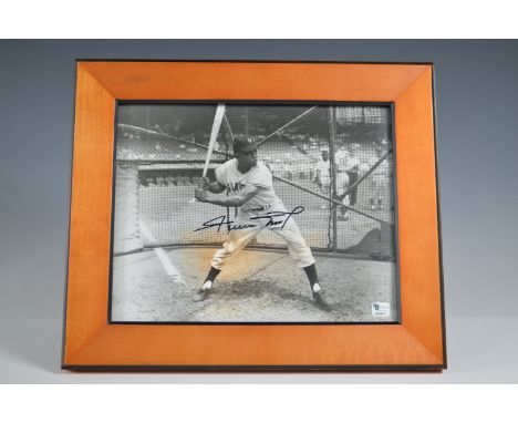 Black and white photograph of baseball legend Willie Mays, captured mid-swing in a batting cage while wearing a San Francisco