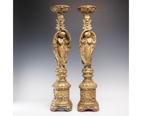 Pair of elaborately carved tall candlestick holders featuring raised angel figures in a prayerful pose. The design showcases 