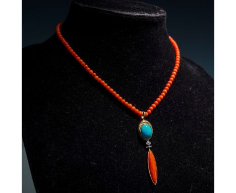 This vibrant necklace features a strand of deep orange-red coral beads, finished with a 14K gold clasp. The drop pendant is m