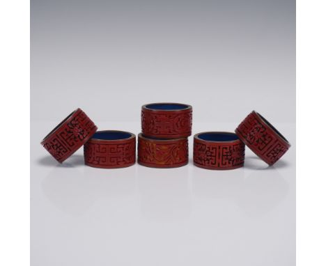 This set of six Chinese cinnabar lacquer napkin rings showcases a rich red lacquer finish intricately hand-carved with tradit