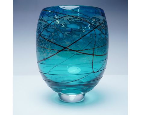 A striking art glass vase featuring a vibrant blue hue with intricate black glass threading creating an organic, web-like pat
