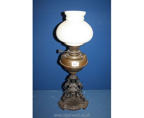 An ornate oil lamp with cast metal base, single burner, white glass shade but no chimney, 24'' tall.