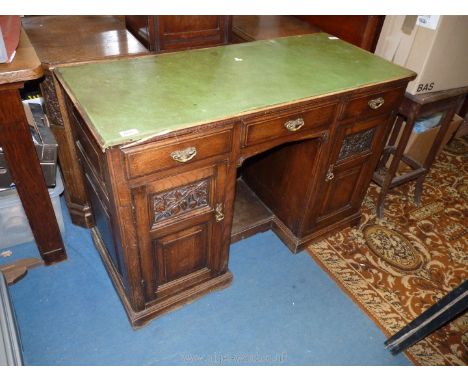 A diminutive circa 1900 Oak Kneehole Desk having three frieze drawers, the kneehole flanked by opposing doors, each with a fr