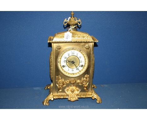 A late 19th c. English gilt brass mantel Clock, ornately cast, surmounted with vase finial with Arabic numerals on a porcelai