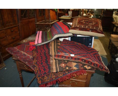 A quantity of textiles including carpet cushions, saddle bag, etc.