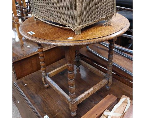 An early 20th Century polished oak occasional table, set on bobbin supports and pommel feet