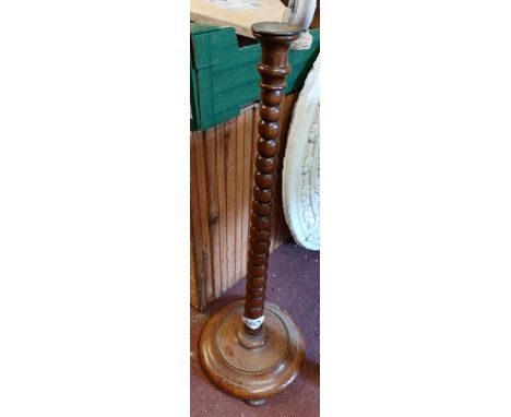 An 80cm high 1920's oak candlestick with brass sconce, bobbin turned pillar and circular base with squat bun feet