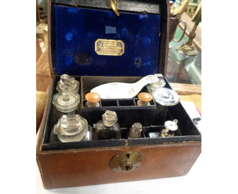 An antique leather apothecary case, the velvet lined fitted interior containing assorted bottles, a measure and a ceramic mea