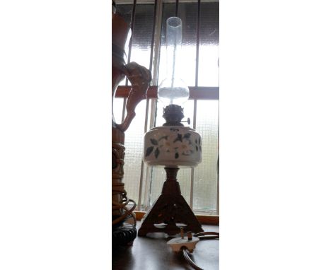 A Victorian oil lamp with stencil decorated opaque glass reservoir and gilt finish cast iron base - with original glass chimn
