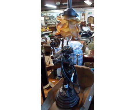 A modern cast resin and metal table lamp in the antique style depicting a child playing a flute with amber glass flower shade