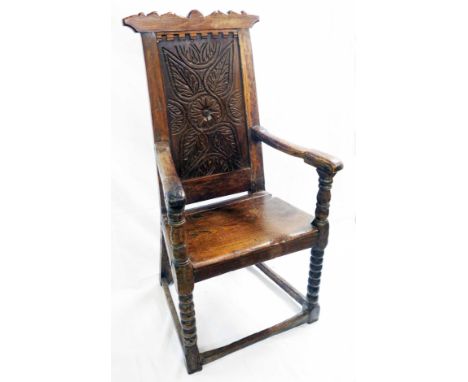 A 17th Century joined oak wainscot armchair chair with later top rail, carved decoration to back panel and solid seat, set on