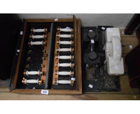 An old wall mounted fuse box with thirteen pull out ceramic fuses on an opaque black glass panel within wooden framing box (g