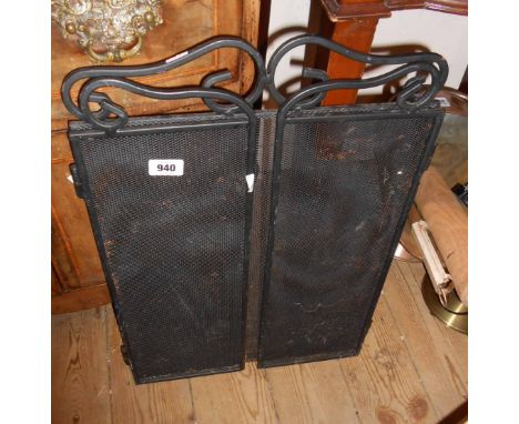 A black painted wrought iron and mesh fire screen