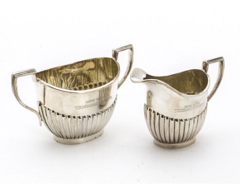A George V silver milk jug and sugar basin from W &amp; EV, helmet shaped with fluted lowers, Sheffield 1911, with engraved i
