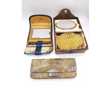 Two silver dressing sets and a python coin purse with silver mounts. The dressing sets contain mirrors, combs and brushes, on