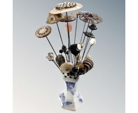 An antique ceramics blue and white hat pin stand containing vintage hat pins 