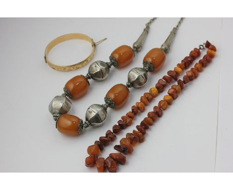 A Middle Eastern silver mounted amber necklace, an amber bead necklace, a gold plated bangle