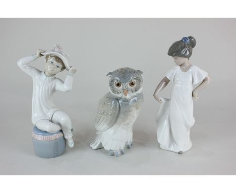 A Lladro porcelain figure of a girl wearing a hat, two Nao porcelain figures of an owl and a girl in white dress