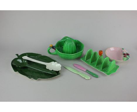 A collection of Carlton ware pottery comprising green glazed citrus squeezer, toast rack, leaf shaped platter and two servers