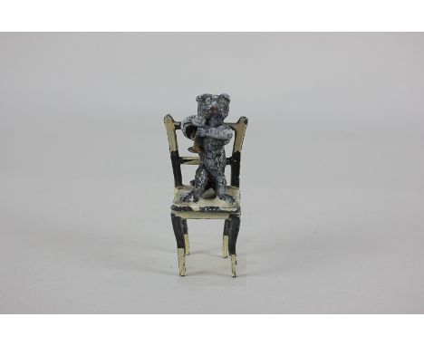 A painted lead figure of a cat playing the trumpet, standing on a chair, 7cm