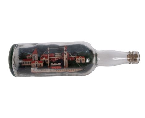 A WWII German Prisoner of War  model ship in a bottle: set on a waterline base with lighthouse and buildings beyond, manuscri