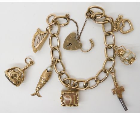 A 9ct gold charm bracelet, with five 9ct gold attached charms, and one loose and a yellow metal fish charm with ruby eyes, we